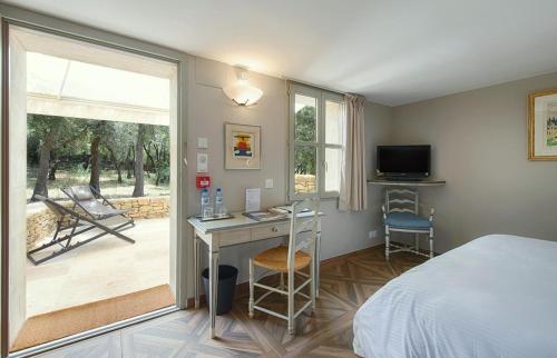 a bedroom with a bed and a desk and a television at Le Jas de Gordes in Gordes