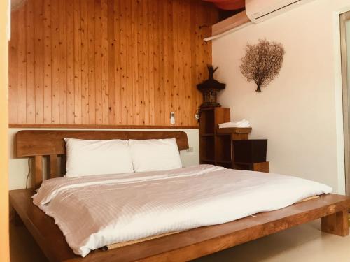 1 dormitorio con 1 cama con pared de madera en 睡海邊-小木屋, en Suao