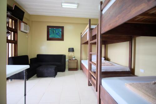 a room with a bunk bed and a couch at Pacific Waves Inn (Annex) in Baler