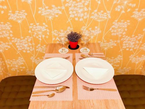 a table with white plates and cutlery on it at Golden Wood Apartments in Plzeň