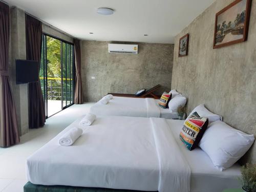 two white beds in a room with a window at Laemsai Resort in Thalang
