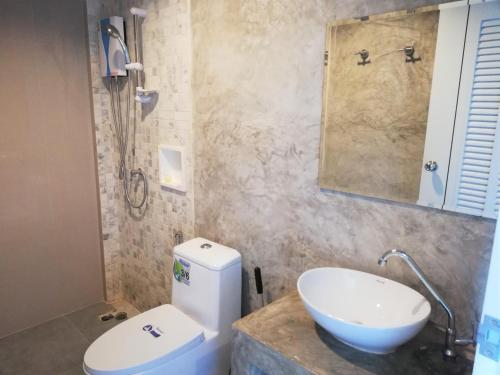 bagno con servizi igienici bianchi e lavandino di Laemsai Resort a Thalang