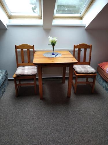 a table with two chairs and a vase with flowers on it at Kulturně Společenské Centrum in Hrušky