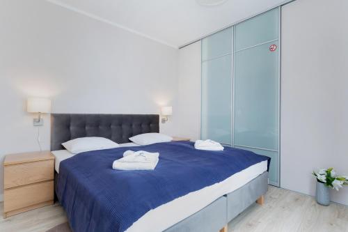 a bedroom with a blue bed with towels on it at Apartamenty Pegaz by Renters in Świnoujście