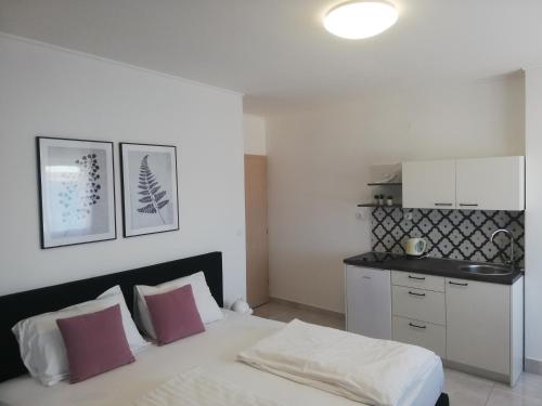 Cet appartement comprend une chambre avec un lit blanc et une cuisine. dans l'établissement Apartment Šušanj, à Karlobag