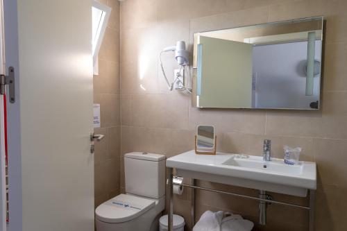 a bathroom with a toilet and a sink and a mirror at Naranjos Resort Menorca in S'Algar