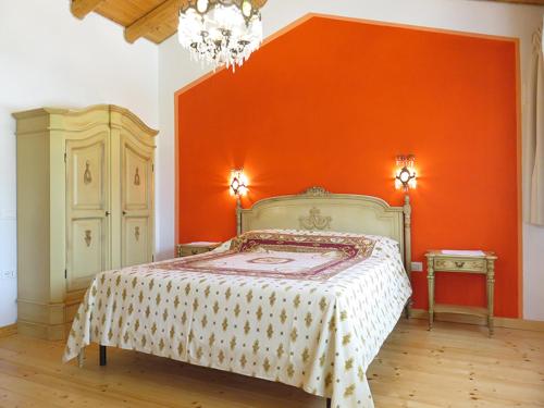 ein Schlafzimmer mit einem Bett mit einer orangefarbenen Wand in der Unterkunft Agriturismo Villa Stella in Rivoli Veronese