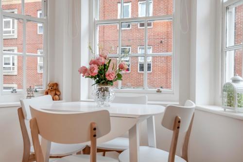 a white dining room with a vase of flowers on a table at Modern One Bedroom Victoria Apartment in London