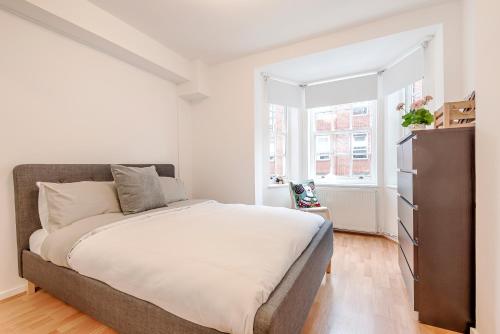 a bedroom with a large bed and a window at Modern One Bedroom Victoria Apartment in London