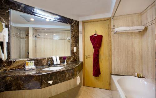a bathroom with a sink and a mirror and a tub at City Seasons Hotel Dubai in Dubai