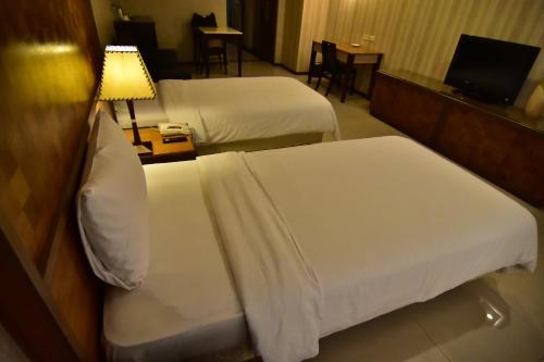 a hotel room with two beds and a table with a lamp at SLV Hotel Group-SLV Business Hotel in Zhonghe