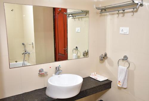 a bathroom with a sink and a mirror at Hotel Amit International in Bhilai