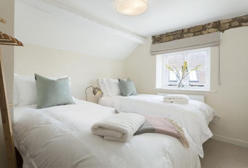 2 weiße Betten in einem Zimmer mit Fenster in der Unterkunft The Bakery in Moreton-in-Marsh