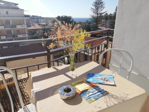 einen Tisch mit einer Blumenvase auf dem Balkon in der Unterkunft OLYMPUS ROOM in Tropea