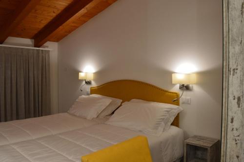 a bedroom with a bed with white sheets and a yellow chair at Agriturismo Ca’ d’Oro in Sarego