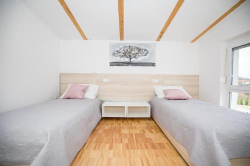 two beds in a room with a tree on the wall at Kuće za odmor -Japin breg in Ðurđevac