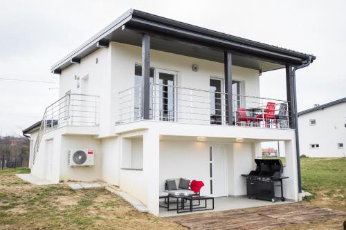 a white house with a balcony and a grill at Kuće za odmor -Japin breg in Ðurđevac