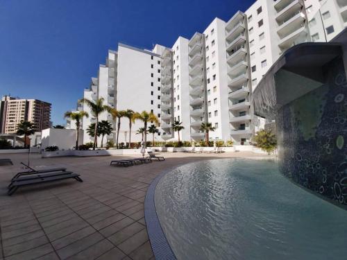a swimming pool in front of a large building at New apartment near the beach in Playa Paraiso in Playa Paraiso