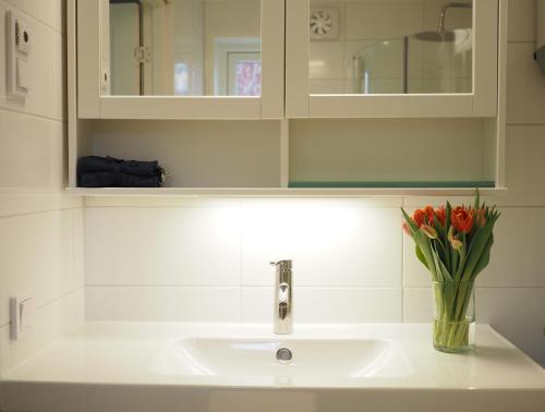 a bathroom sink with a vase of flowers on it at Kristina Attefall i Västerhaninge in Västerhaninge