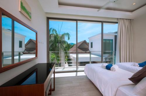 een slaapkamer met een tv en een groot raam bij Laem Ka Residence by Tropiclook in Rawai Beach