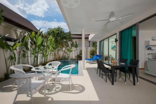 a patio with a table and chairs and a pool at Laem Ka Residence by Tropiclook in Rawai Beach