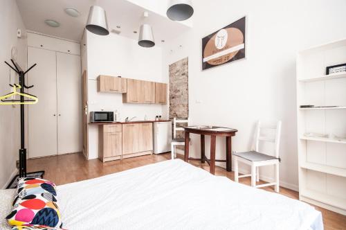 a bedroom with a white bed and a kitchen at Apartment in the center of Warsaw in Warsaw