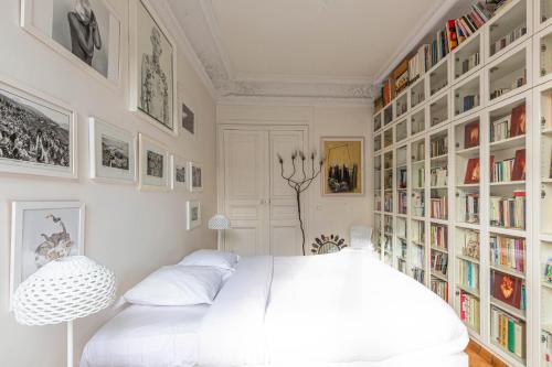 una camera con un grande letto bianco e librerie di Veeve - La Fayette Light a Parigi