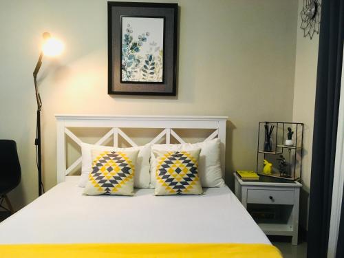 a bedroom with a white bed with yellow and blue pillows at BH Mangrove Condos in Mactan