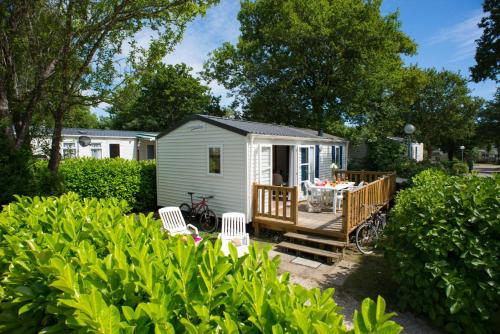 a tiny house with a deck and chairs at Siblu camping in de Bongerd in Oostkapelle