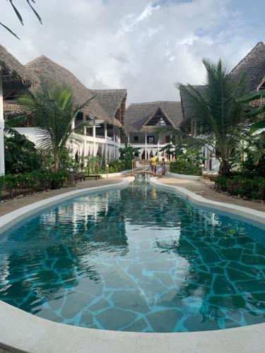 a swimming pool in front of a villa at Rafiki Village in Watamu