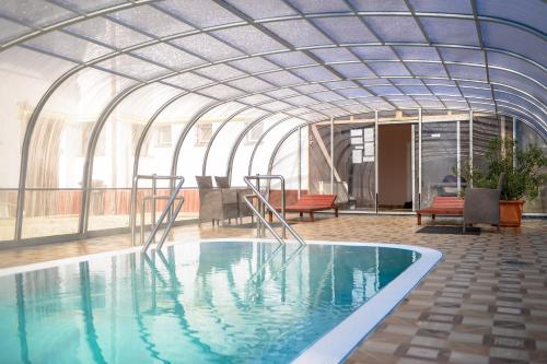 a swimming pool in a building with a glass ceiling at Thermal Panzió Igal in Igal