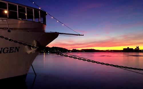 a boat docked in the water at sunset at Mälardrottningen Yacht Hotel in Stockholm