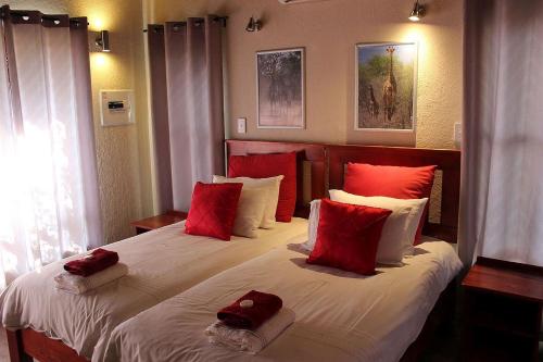 a bedroom with two beds with red and white pillows at Woodpecker Lodge B&B in Hoedspruit