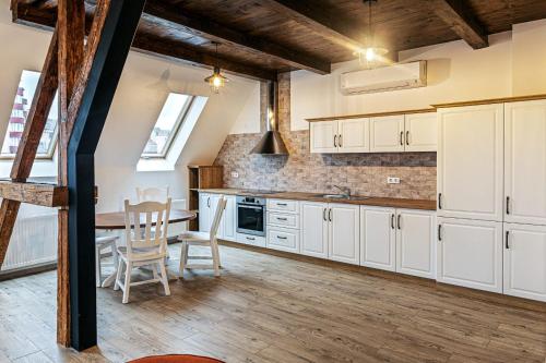 a kitchen with white cabinets and a table and chairs at Apartament The Bricks 1903 in Bistriţa