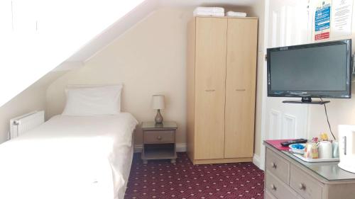 a bedroom with a bed and a flat screen tv at The George Guest House in Plymouth