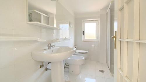 a white bathroom with a sink and a toilet at Casa Vacanze Angelo in Palinuro