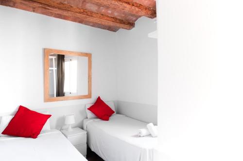 two beds in a white room with red pillows at My Address in Barcelona Old Town in Barcelona