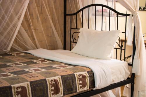 a bed with a black frame and a white pillow at Octagon Lodge in Karatu