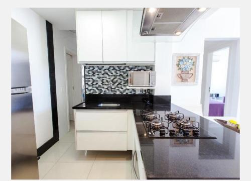 cocina con armarios blancos y fogones en Apartamento Ed Cadima, en Río de Janeiro