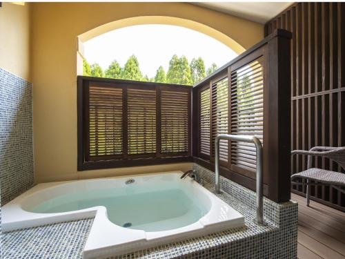 a bath tub in a room with a window at La Vista Kirishima Hills in Kirishima