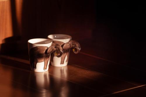 two cups on a table with a toy elephant in them at Tuskers Hill by Poppys Anaikatti in Palghat