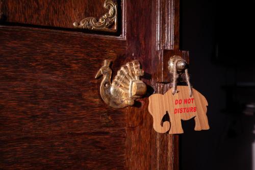 a wooden door with a do not disturb sign on it at Tuskers Hill by Poppys Anaikatti in Palghat