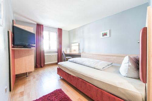 um quarto de hotel com uma cama e uma televisão de ecrã plano em Badischer Hof em Bühl