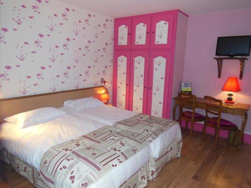 a bedroom with a bed and a desk and a tv at Hotel Le Bellevue in Saint-Hippolyte