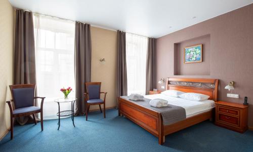 1 dormitorio con 1 cama, 2 sillas y mesa en Nevsky Grand Apartments, en San Petersburgo