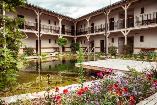 a courtyard of a building with a pond and flowers at Penzión & Wellness MERIDIANA Bojnice rezort in Bojnice