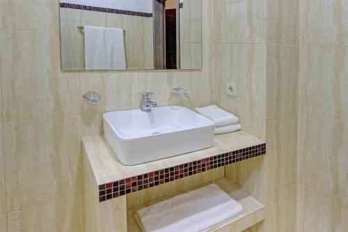 a bathroom with a sink and a mirror and towels at Resident Hotel Almaty in Almaty