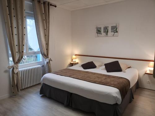 Un dormitorio con una cama grande y una ventana en Les Camelias, en Bagnoles de l'Orne