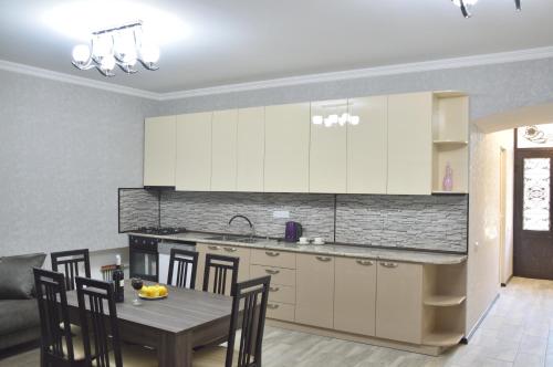 una cocina con armarios blancos y una mesa con sillas. en Mtatsmindaze en Tiflis