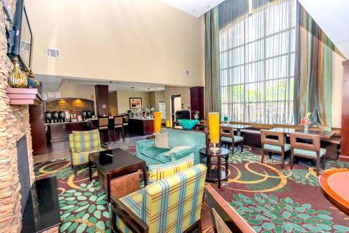a hotel room with a lobby with chairs and tables at Staybridge Suites Houston - IAH Airport by IHG in Houston